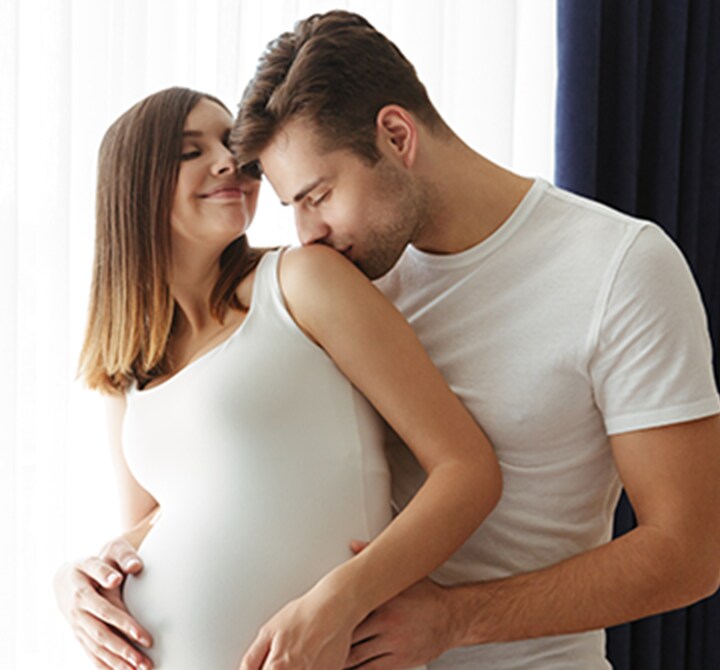 Happy young husband kissing his smiling pregnant wife